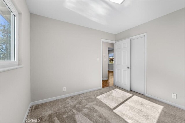 unfurnished bedroom with carpet floors, baseboards, and a closet