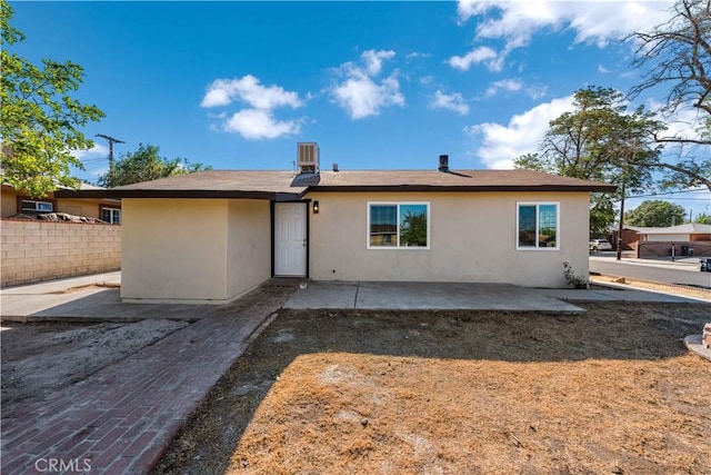 back of property with fence, stucco siding, a patio area, and central AC