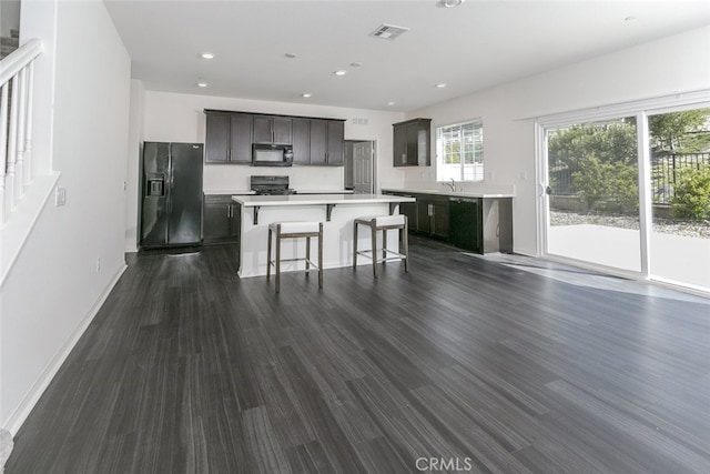 27488 Ginger Ct, Saugus, CA 91350 - kitchen with a center island, visible vents, dark wood-type flooring, black appliances, and light countertops