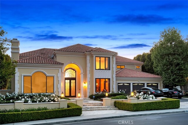 exterior space with an attached garage, a chimney, a tile roof, and stucco siding