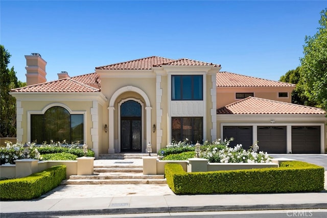 mediterranean / spanish-style house featuring a tiled roof, driveway, a chimney, an attached garage, and stucco siding