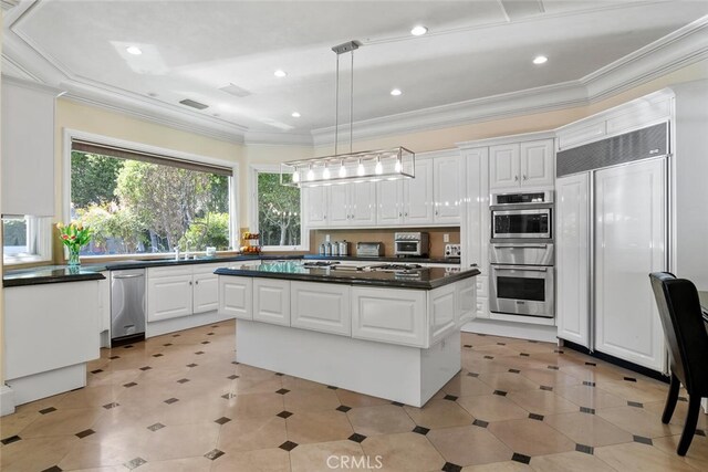 kitchen with a kitchen island, dark countertops, white cabinets, decorative light fixtures, and stainless steel appliances