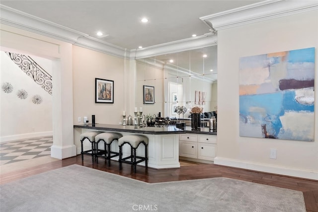 bar featuring crown molding, wood finished floors, baseboards, recessed lighting, and wet bar