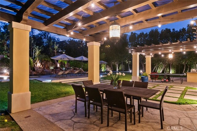 patio at twilight with a pergola, outdoor dining area, and a yard