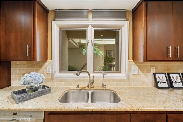 kitchen featuring a sink, light stone countertops, backsplash, and dishwasher