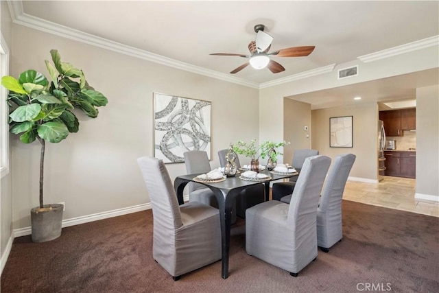 dining room with light colored carpet, ceiling fan, visible vents, and ornamental molding