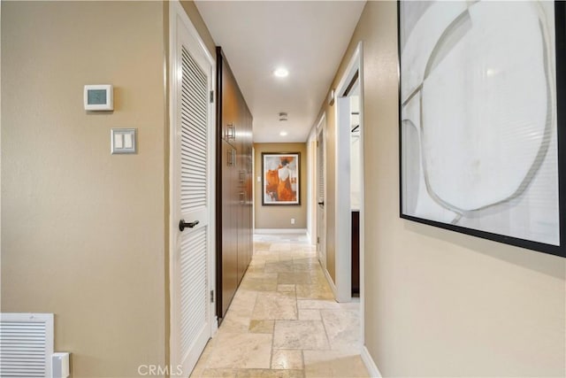 corridor with stone tile flooring, recessed lighting, and baseboards