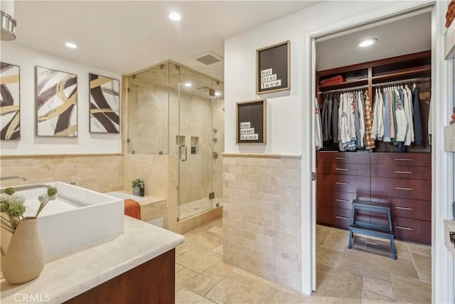full bath featuring vanity, tile walls, a stall shower, and recessed lighting