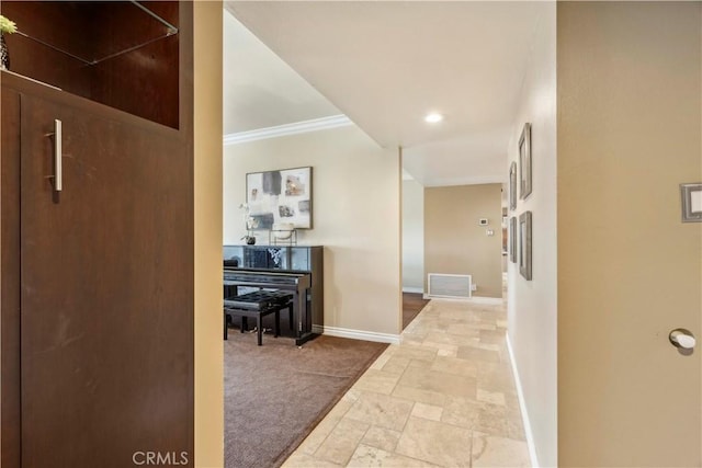 hallway with baseboards, visible vents, ornamental molding, and stone tile flooring