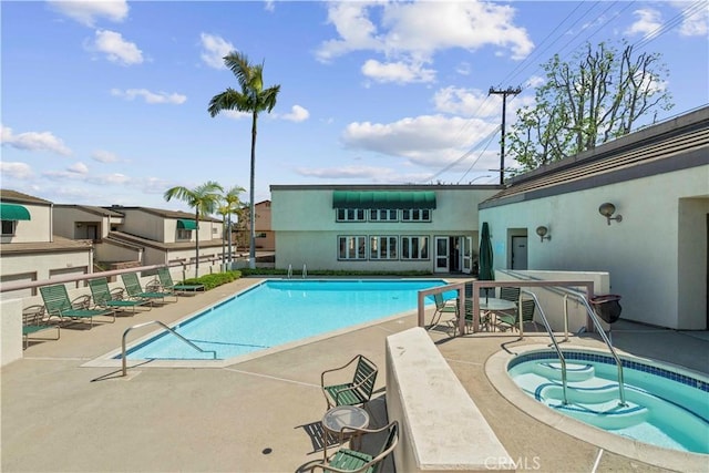 community pool with a patio and a hot tub