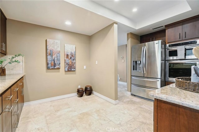 kitchen featuring light stone countertops, appliances with stainless steel finishes, baseboards, and visible vents