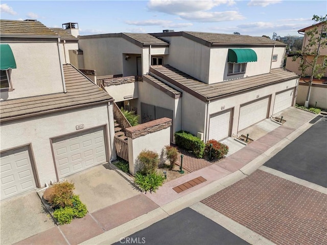 view of front of house featuring a garage, stucco siding, driveway, and a tile roof