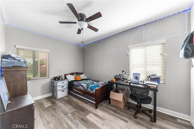 bedroom featuring wood finished floors, baseboards, and ceiling fan