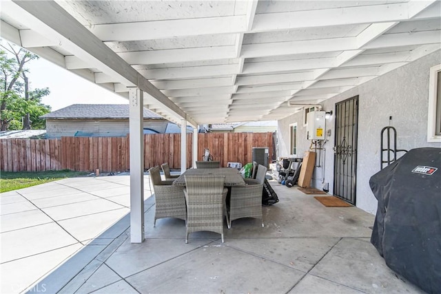 view of patio with outdoor dining space, a fenced backyard, water heater, and area for grilling