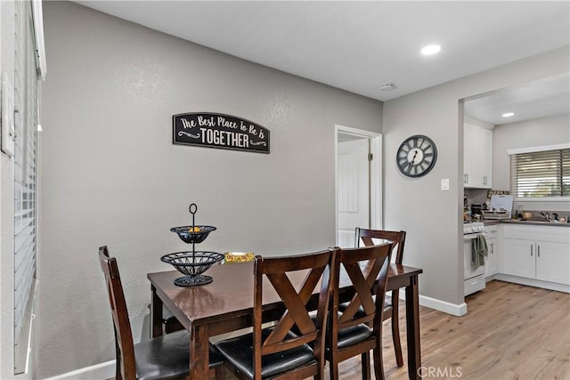 dining room with light wood-type flooring, recessed lighting, and baseboards