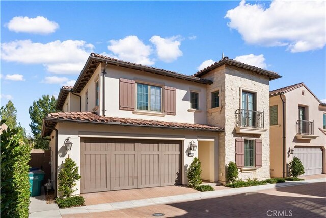 mediterranean / spanish-style home featuring a tile roof, a balcony, and a garage