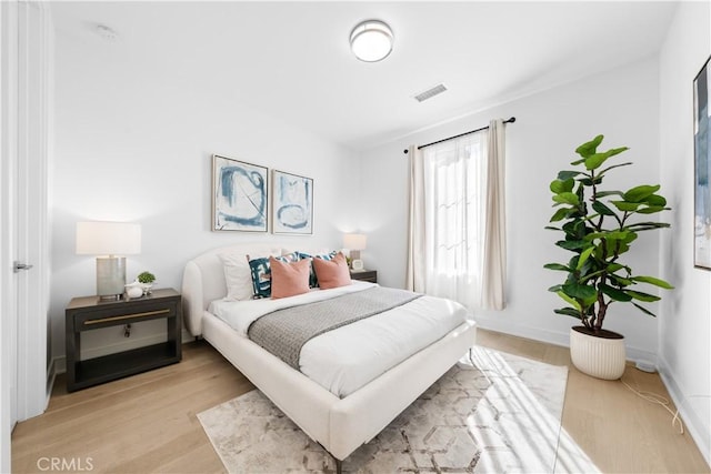 bedroom with visible vents, light wood-style floors, and baseboards