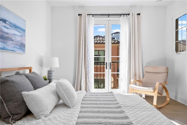 bedroom with baseboards, french doors, wood finished floors, and access to exterior