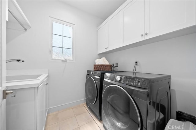 washroom featuring cabinet space, a sink, baseboards, light tile patterned floors, and washer and dryer