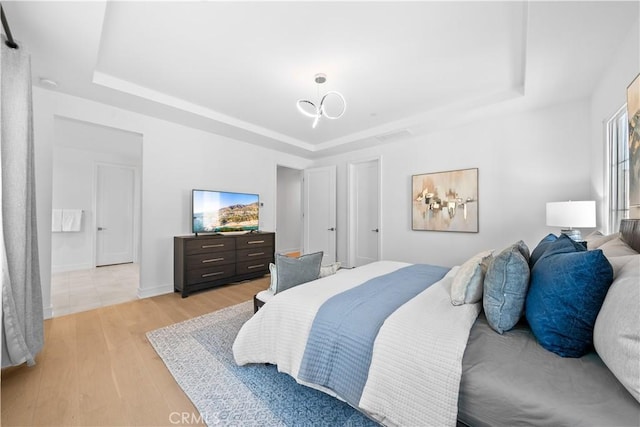 bedroom featuring a raised ceiling and light wood-type flooring