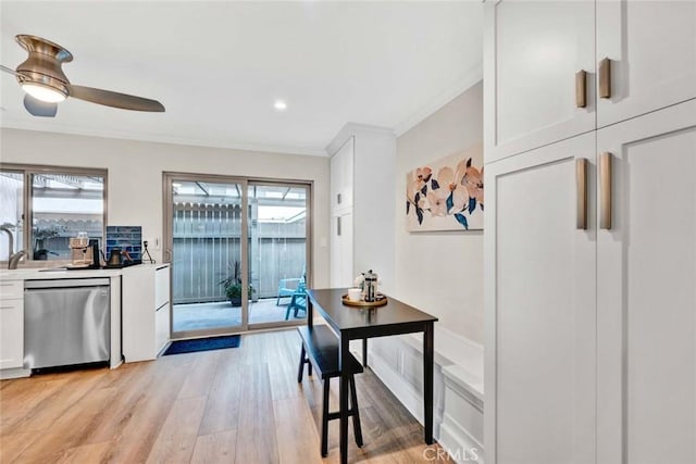 6702 Sun Dr Unit C, Huntington Beach, CA 92647 - kitchen with light wood finished floors, white cabinetry, a ceiling fan, stainless steel dishwasher, and ornamental molding