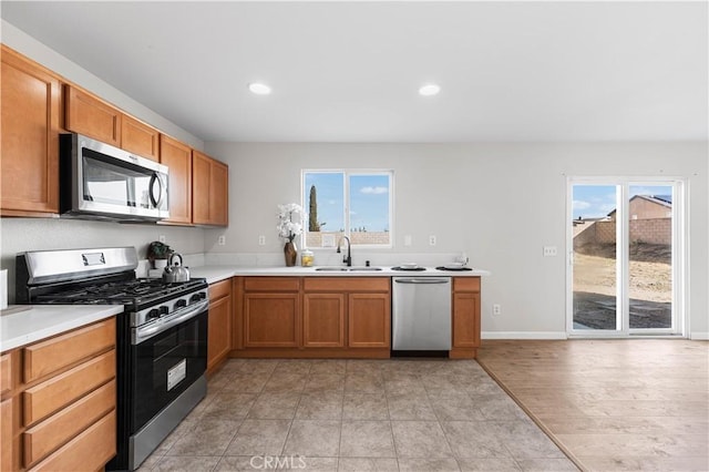 42570 72nd St W, Lancaster, CA 93536 - kitchen featuring brown cabinetry, recessed lighting, light countertops, a sink, and stainless steel appliances