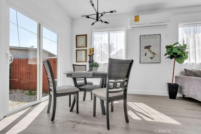 dining room with an inviting chandelier, baseboards, a wall unit AC, wood finished floors, and ornamental molding