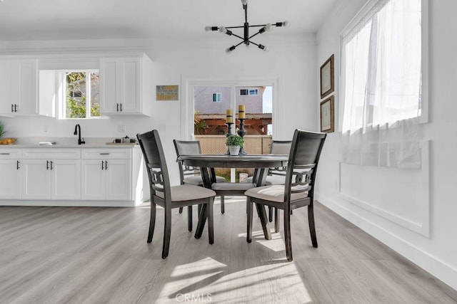 dining space featuring baseboards, light wood-style flooring, and a notable chandelier