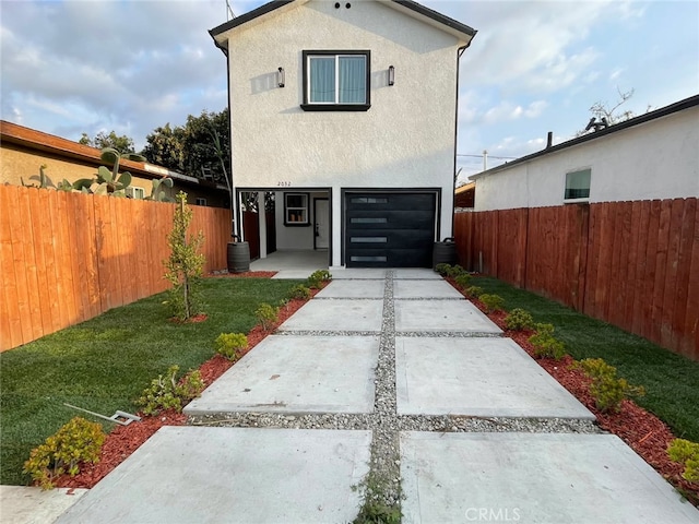 exterior space featuring concrete driveway, fence, a front yard, and stucco siding