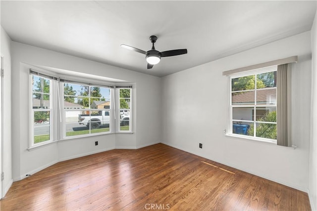 unfurnished room with baseboards, plenty of natural light, a ceiling fan, and wood finished floors