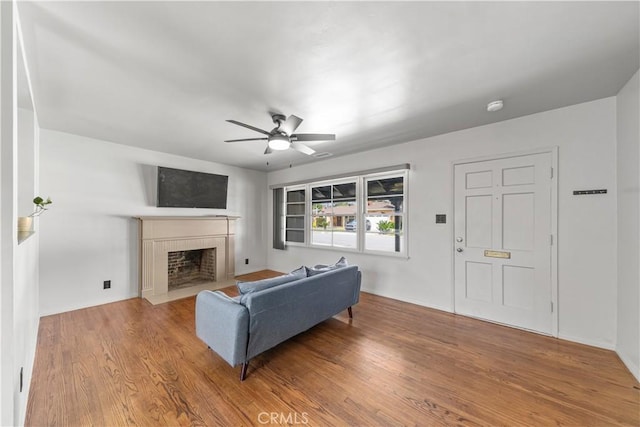 living room featuring a fireplace with flush hearth, a ceiling fan, and wood finished floors