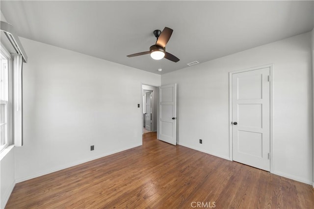 unfurnished bedroom featuring visible vents, baseboards, ceiling fan, and wood finished floors