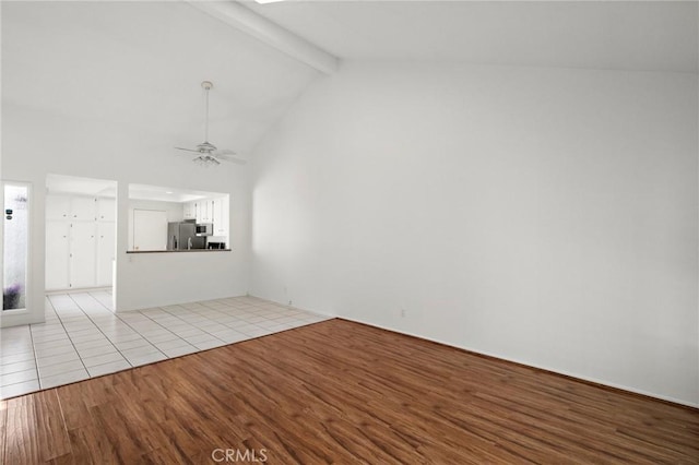 unfurnished living room with a ceiling fan, light wood finished floors, beam ceiling, and high vaulted ceiling