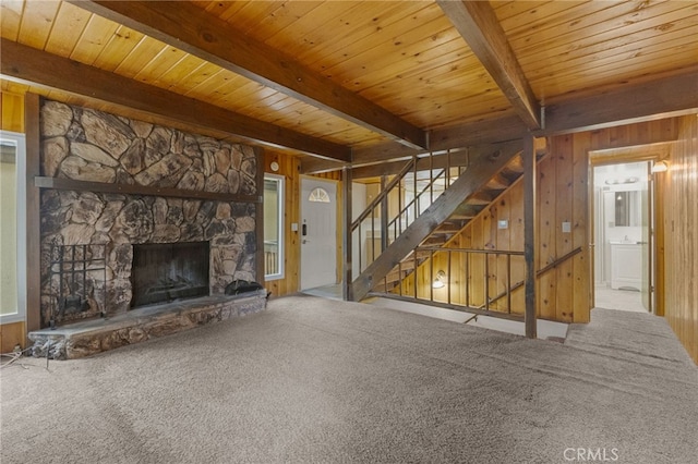 2368 Pine Dr, Running Springs, CA 92382 - unfurnished living room with wood walls, carpet, a wooden ceiling with exposed beams, a stone fireplace, and stairway