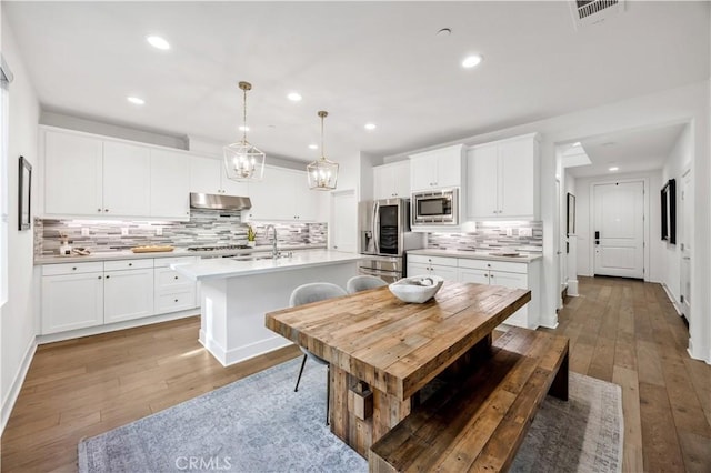 1253 Viejo Hills Dr, Lake Forest, CA 92610 - kitchen featuring stainless steel appliances, under cabinet range hood, light wood-type flooring, backsplash, and recessed lighting