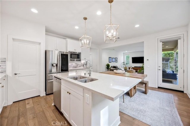 1253 Viejo Hills Dr, Lake Forest, CA 92610 - kitchen with a sink, stainless steel appliances, a chandelier, white cabinets, and light wood-type flooring