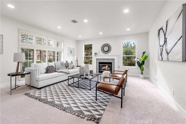 carpeted living area with a glass covered fireplace, baseboards, recessed lighting, and visible vents