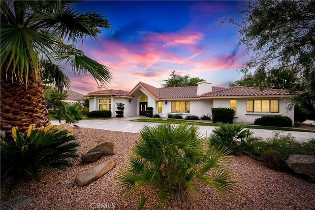 mediterranean / spanish-style home with concrete driveway, stucco siding, and a chimney