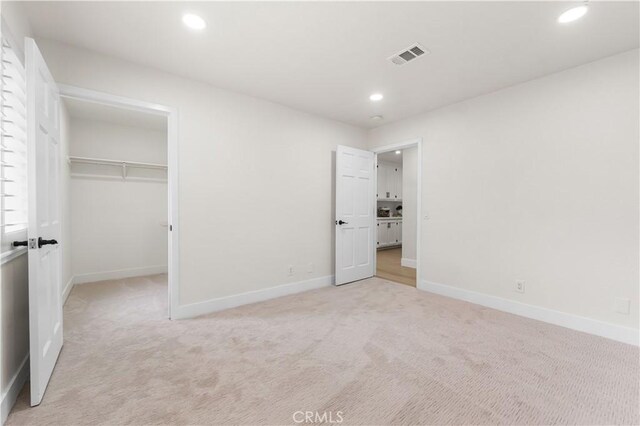unfurnished bedroom featuring baseboards, light colored carpet, recessed lighting, and visible vents