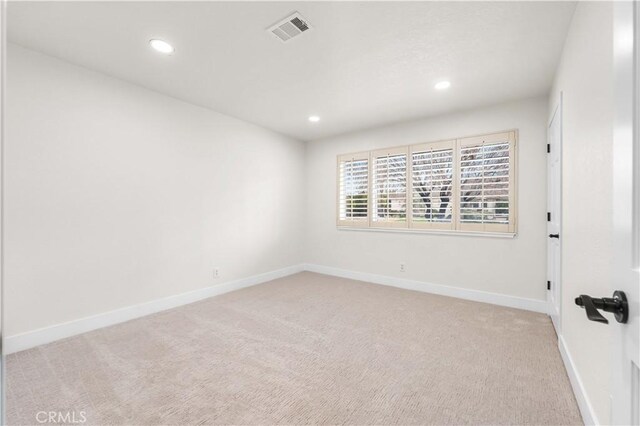 empty room with baseboards, light colored carpet, and visible vents