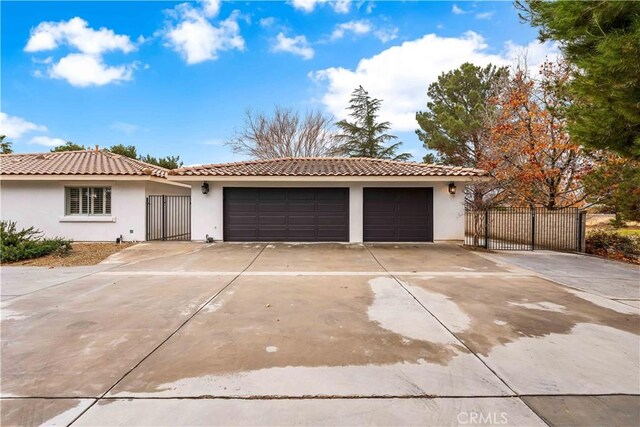 view of front of property with concrete driveway, a tiled roof, a garage, and stucco siding