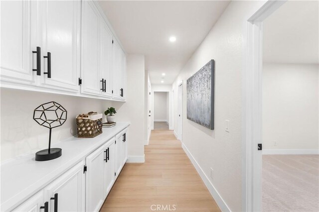 hallway with recessed lighting, light wood-style flooring, and baseboards