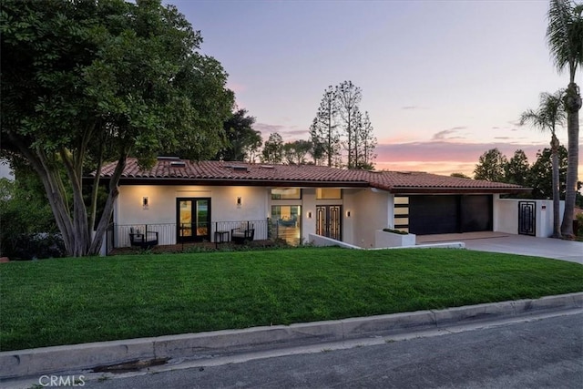 view of front of house featuring a tile roof, a garage, stucco siding, concrete driveway, and french doors