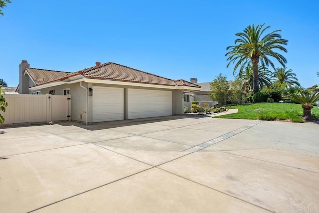 view of front of house with a tiled roof, fence, stucco siding, and a garage