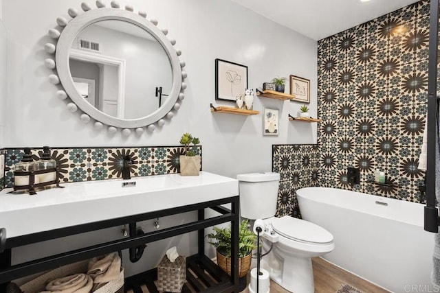 full bathroom with visible vents, vanity, wood finished floors, toilet, and a soaking tub