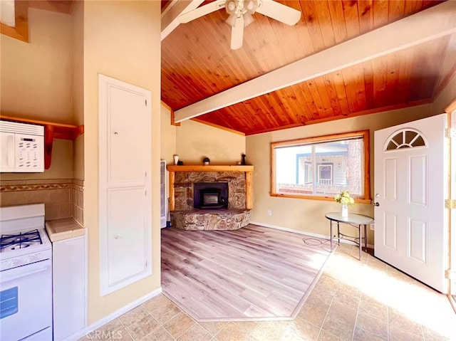interior space featuring ceiling fan, white appliances, a stone fireplace, tile countertops, and wooden ceiling