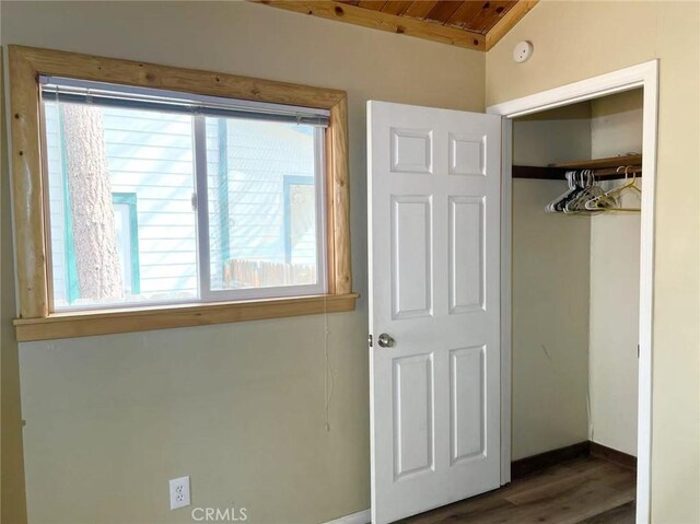 unfurnished bedroom featuring baseboards, multiple windows, a closet, and wood finished floors