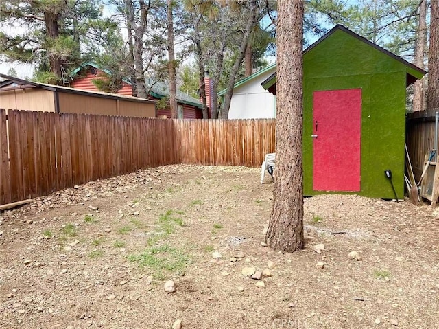 view of yard featuring a fenced backyard, an outdoor structure, and a storage shed