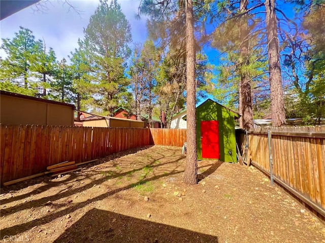 view of yard featuring a storage shed, an outbuilding, and a fenced backyard