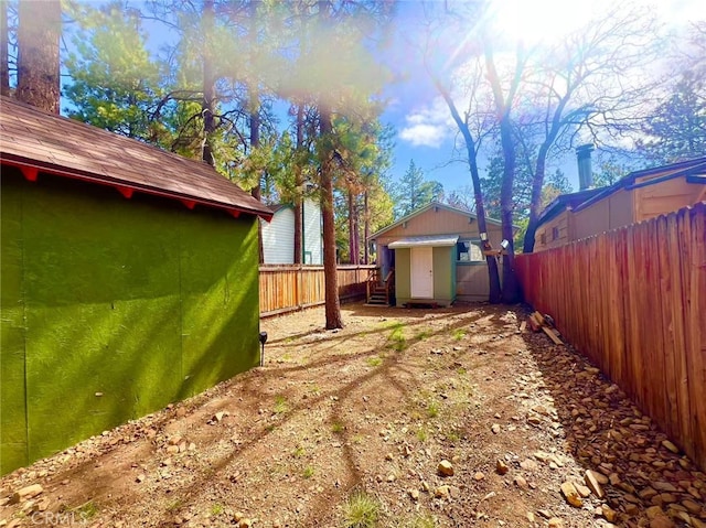 view of yard featuring a fenced backyard, an outdoor structure, and a shed